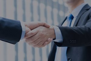 Close-up of two people in business suits shaking hands, with a dark blue filter.