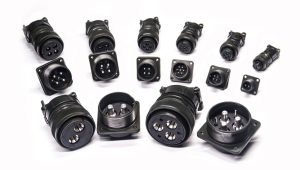 An assortment of black, cylindrical, multi-pin electrical connectors, including both chassis-mount receptacles and cable-mount plugs, displayed against a white background.